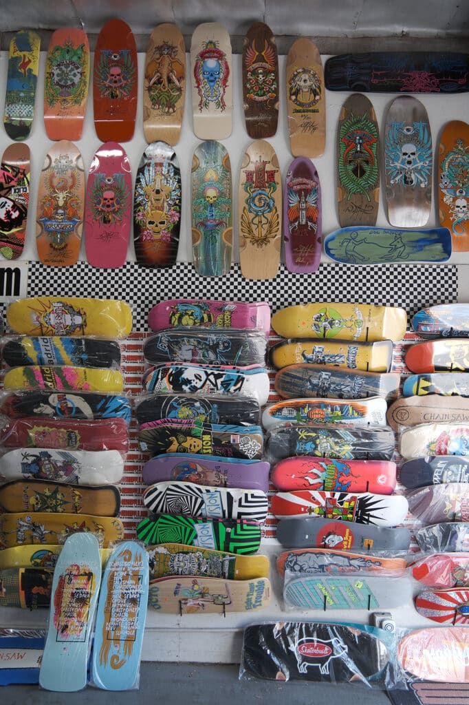 Shapers-Club- Un assortiment de planches de skateboard colorées, dont des modèles Gordon et Smith, exposées sur un mur. -surfshop-surfboard