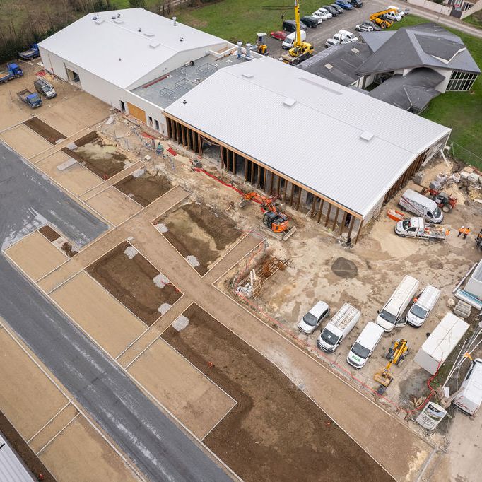 Shapers-Club- Vue aérienne d'un chantier avec travaux en cours sur un grand bâtiment par l'UWL et véhicules stationnés à proximité. -surfshop-surfboard