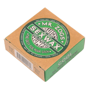Shapers-Club- Une petite boîte en carton de Sexwax - Cool Surfboard Wax, avec une marque verte et blanche. L'étiquette affiche bien en évidence « Sexwax », « Quick Humps » et « The best for your stick ». La boîte indique qu'elle est conçue pour les températures fraîches à moyennement chaudes, qu'elle a une texture douce et qu'elle pèse 85 grammes. -surfshop-surfboard