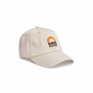 Shapers-Club- Une casquette SUNRISE DAD blanche sale avec un bord incurvé et un motif brodé sur le devant, présentant un graphique de coucher de soleil orange et marron avec les mots « DEUS CUSTOMS » en dessous. -surfshop-surfboard