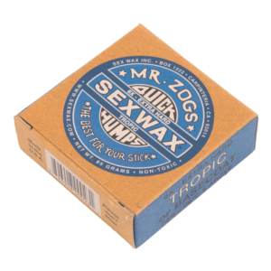 Shapers-Club- A brown and blue can of Sexwax - Tropic Basecoat by Mr. Zog, labeled "Quick Humps Tropic" and "The Best for Your Stick". The box says it's extra hard, non-toxic and weighs 85 grams. Ideal as a base layer for your board. -surfshop-surfboard